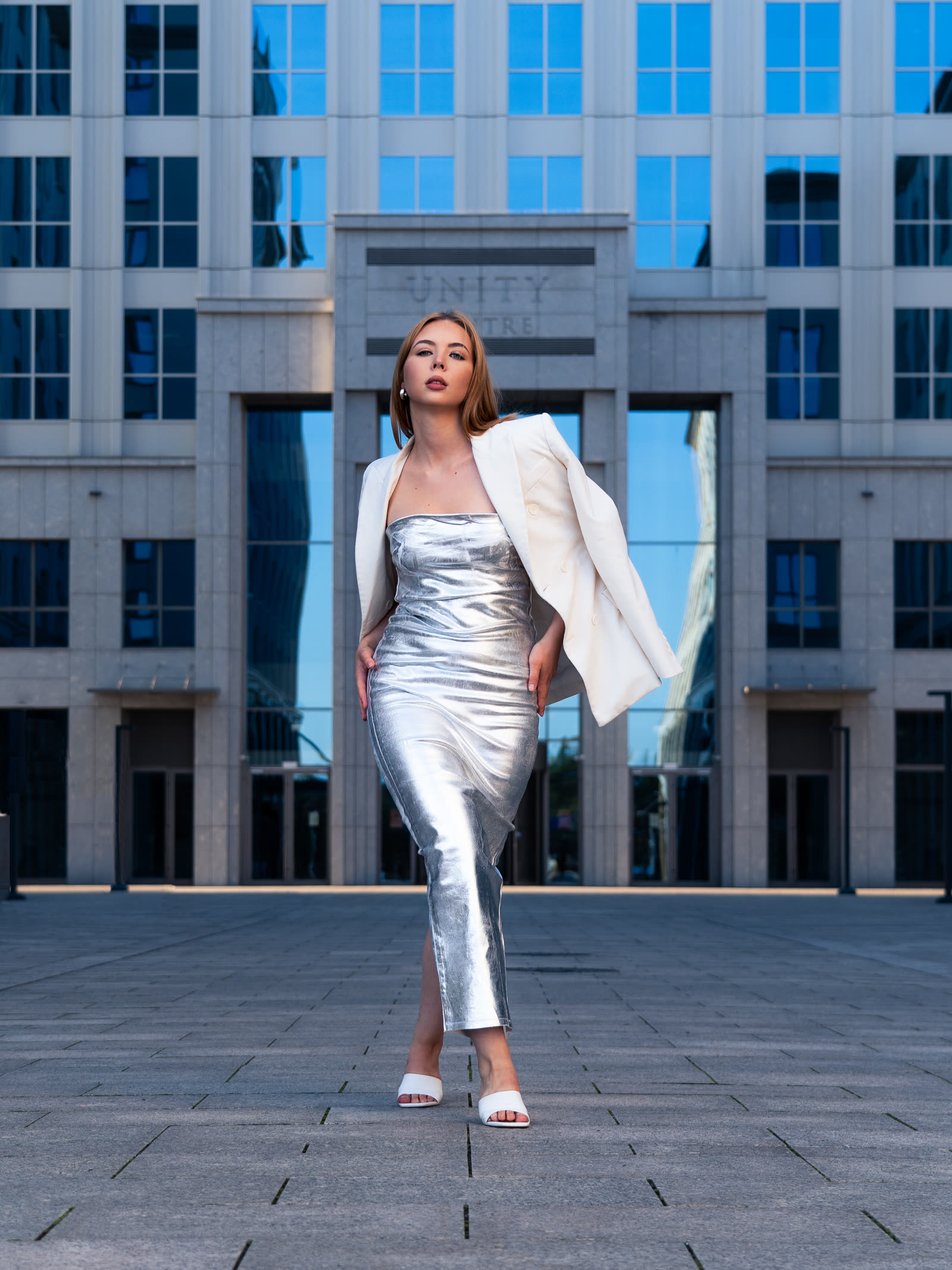 Editorial fashion session in Kraków — woman in a silver dress in front of Unity Centre, photographer Dawid Szotek