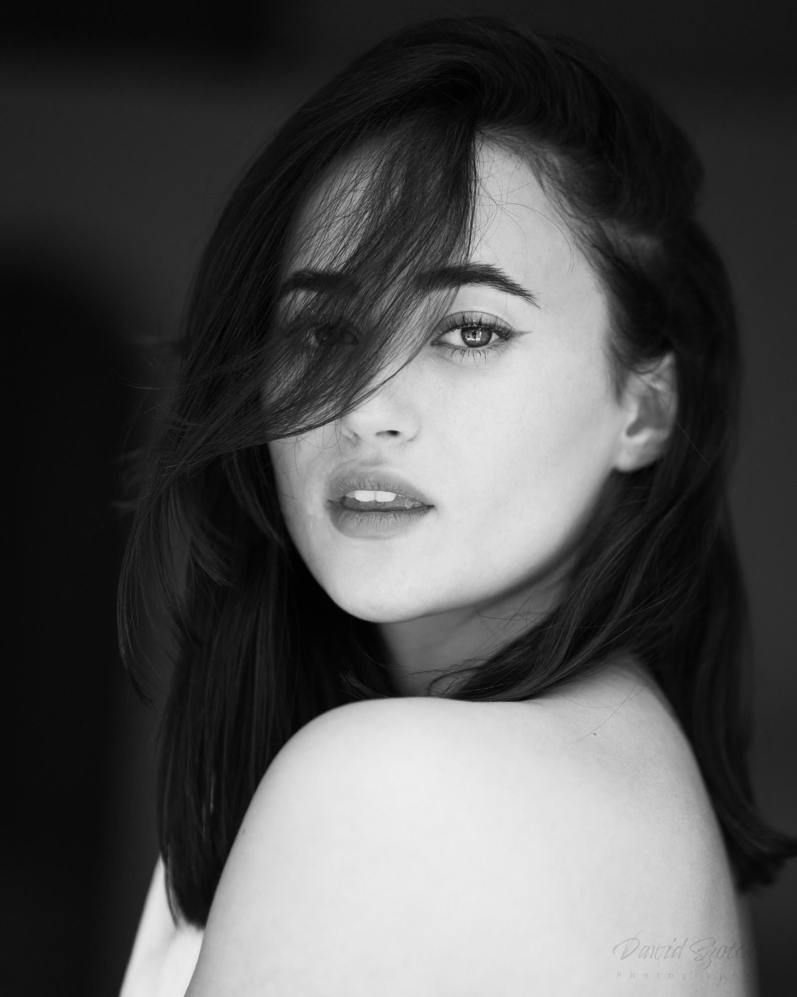 Black and white women's portrait — intimate gaze, hair falling on the face, fine art photography Kraków