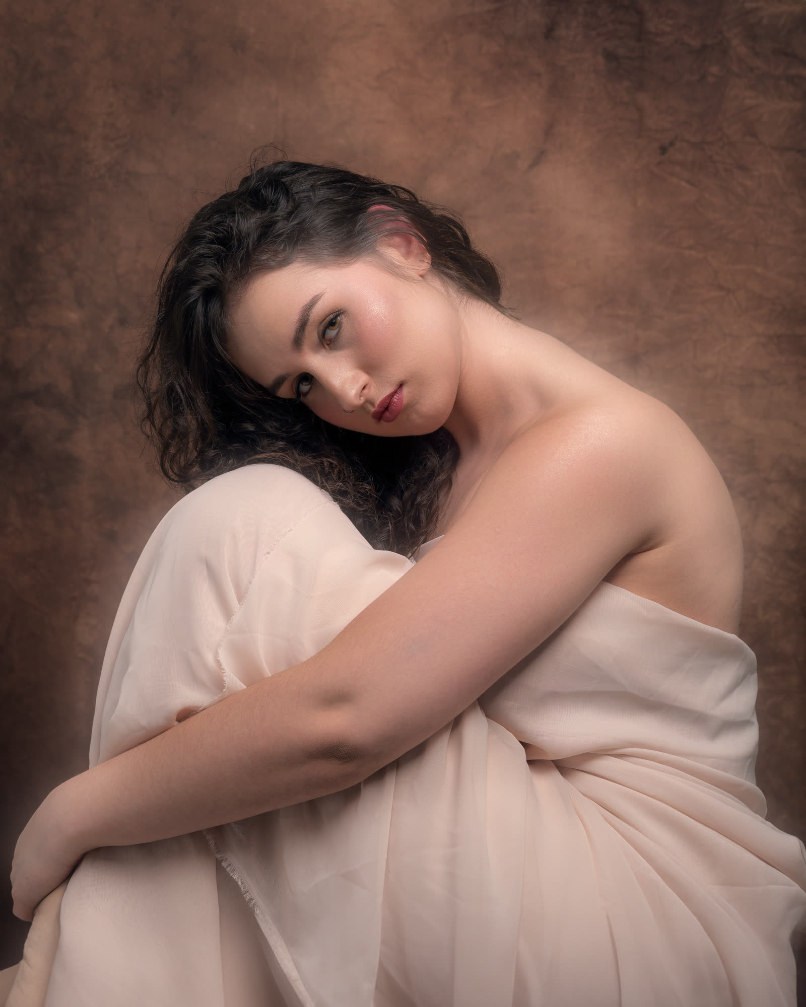Fine art portrait session — woman draped in light fabric on a warm background, painterly composition, portrait photographer Kraków