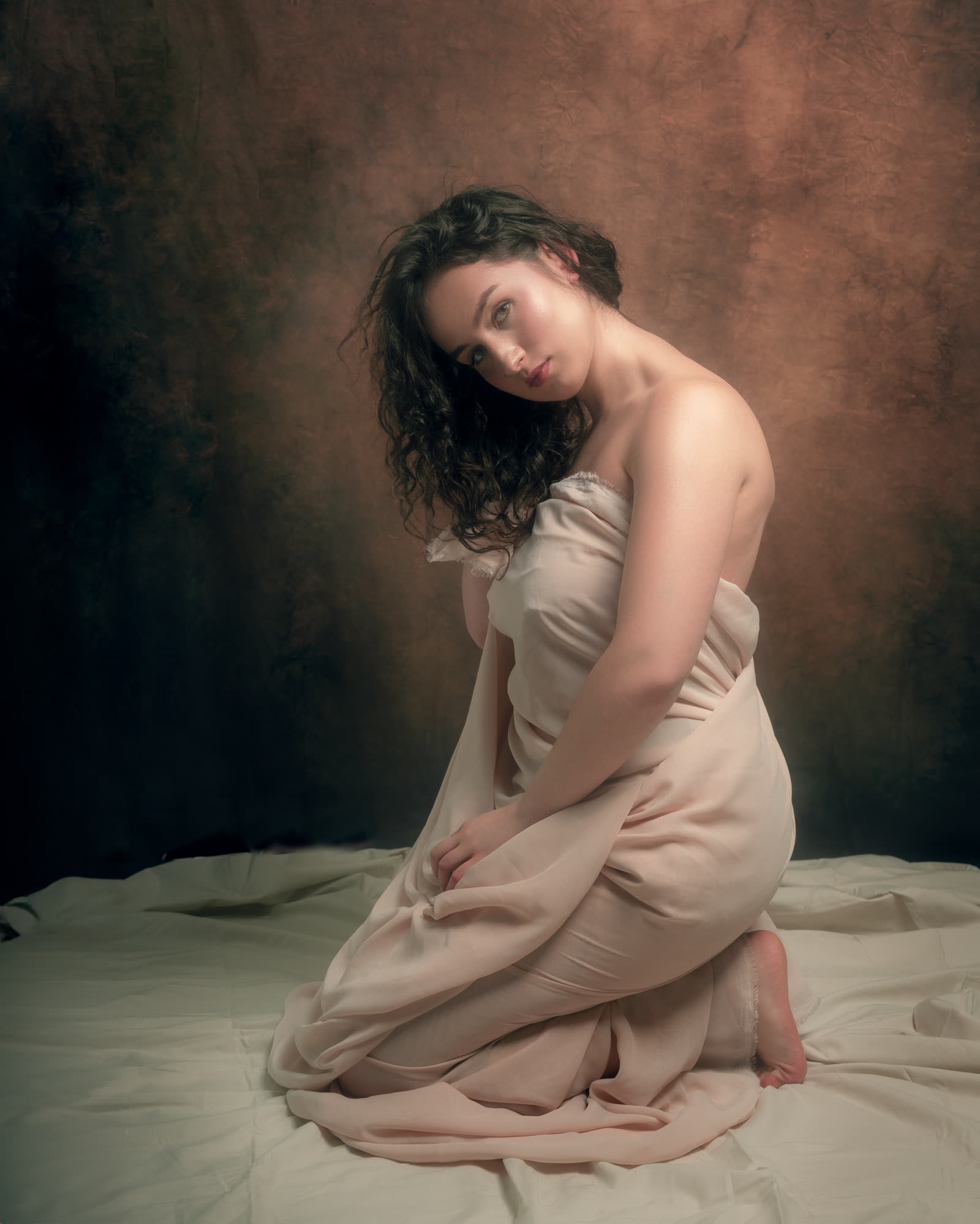 Fine art women's session — woman seated, draped in silk fabric, studio art session
